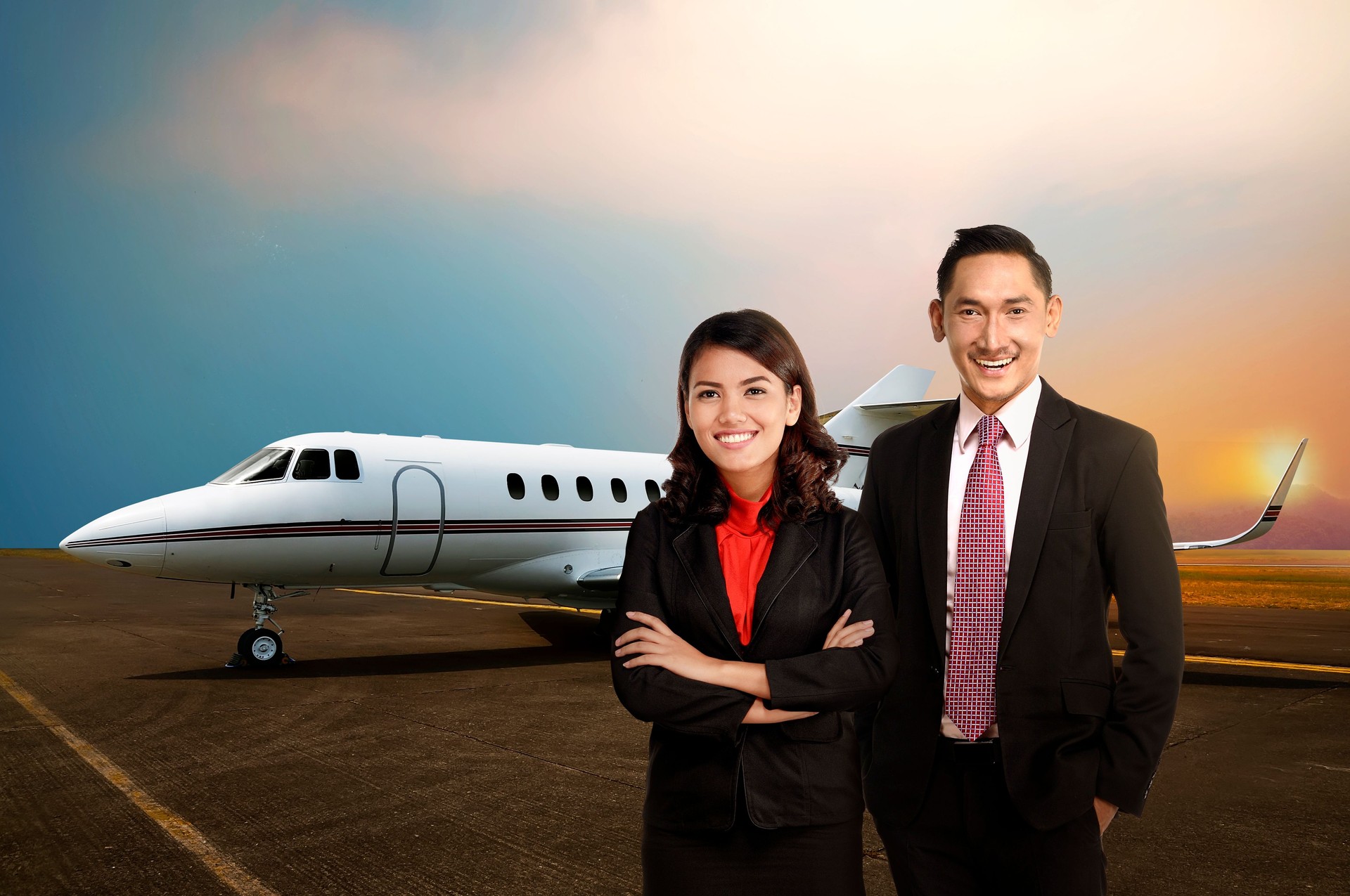Business man and woman smiling in front of private jet