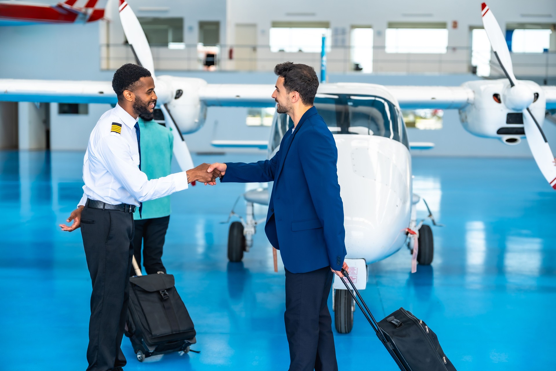 Pilot shaking hands with businessman in hangar